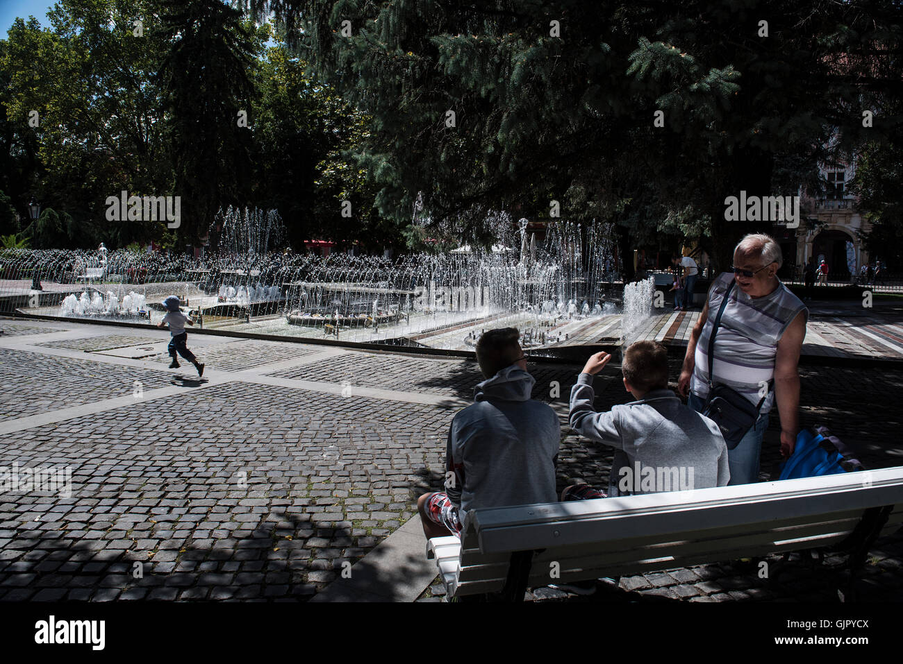 La gente guarda come una bambina corre vicino alla Fontana Cantante al centro della città di Kosice in Slovacchia Foto Stock