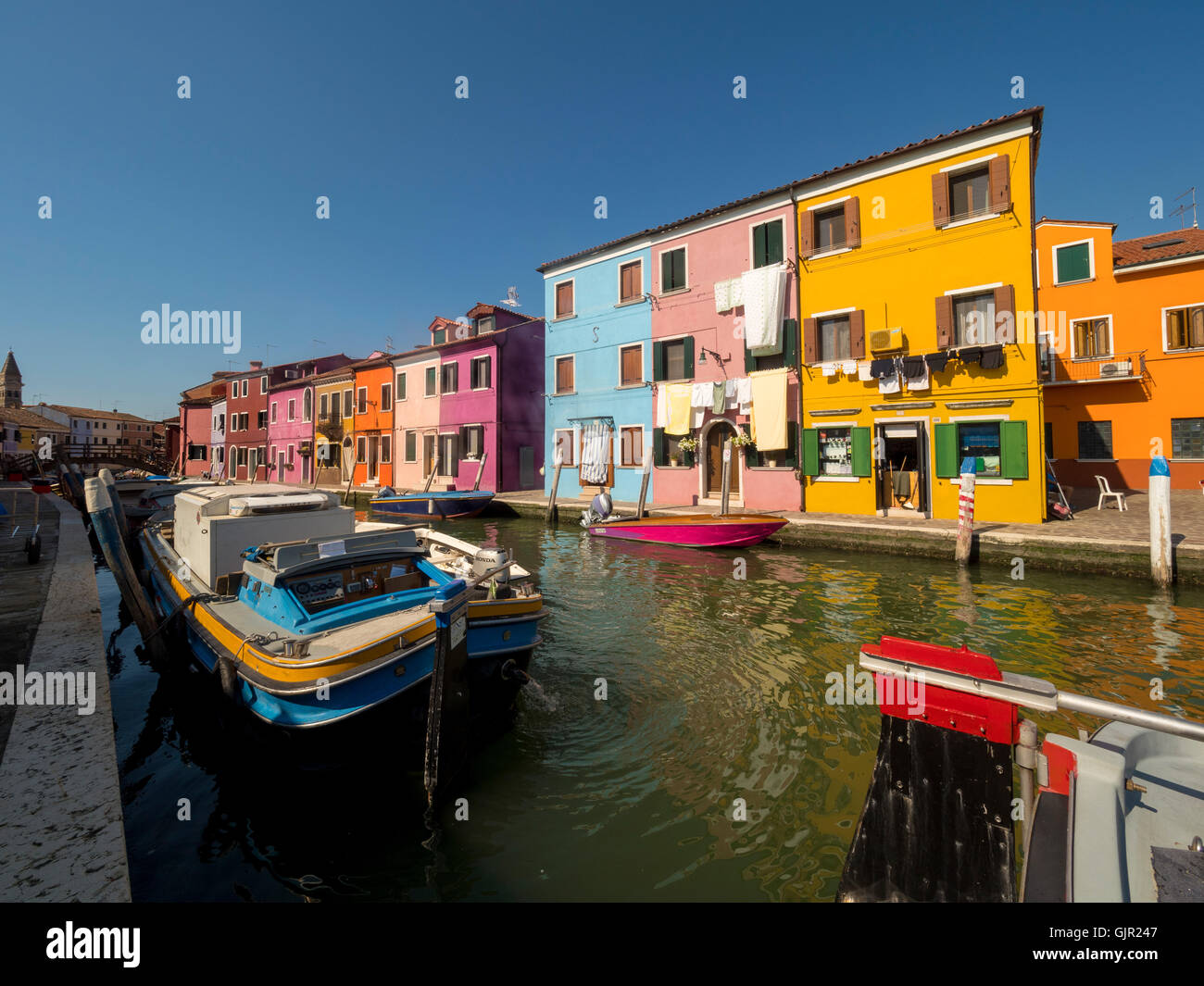 Case con terrazza in riva al mare dipinte con colori vivaci sull'isola di Burano. Venezia, Italia. Foto Stock