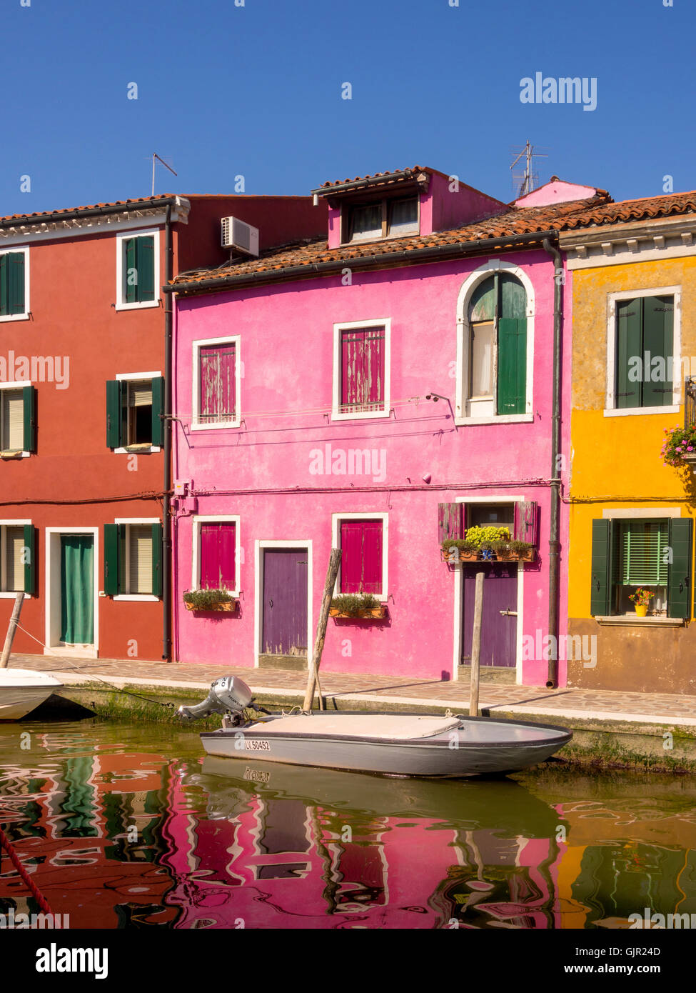 Case con terrazza in riva al mare dipinte con colori vivaci sull'isola di Burano. Venezia, Italia. Foto Stock
