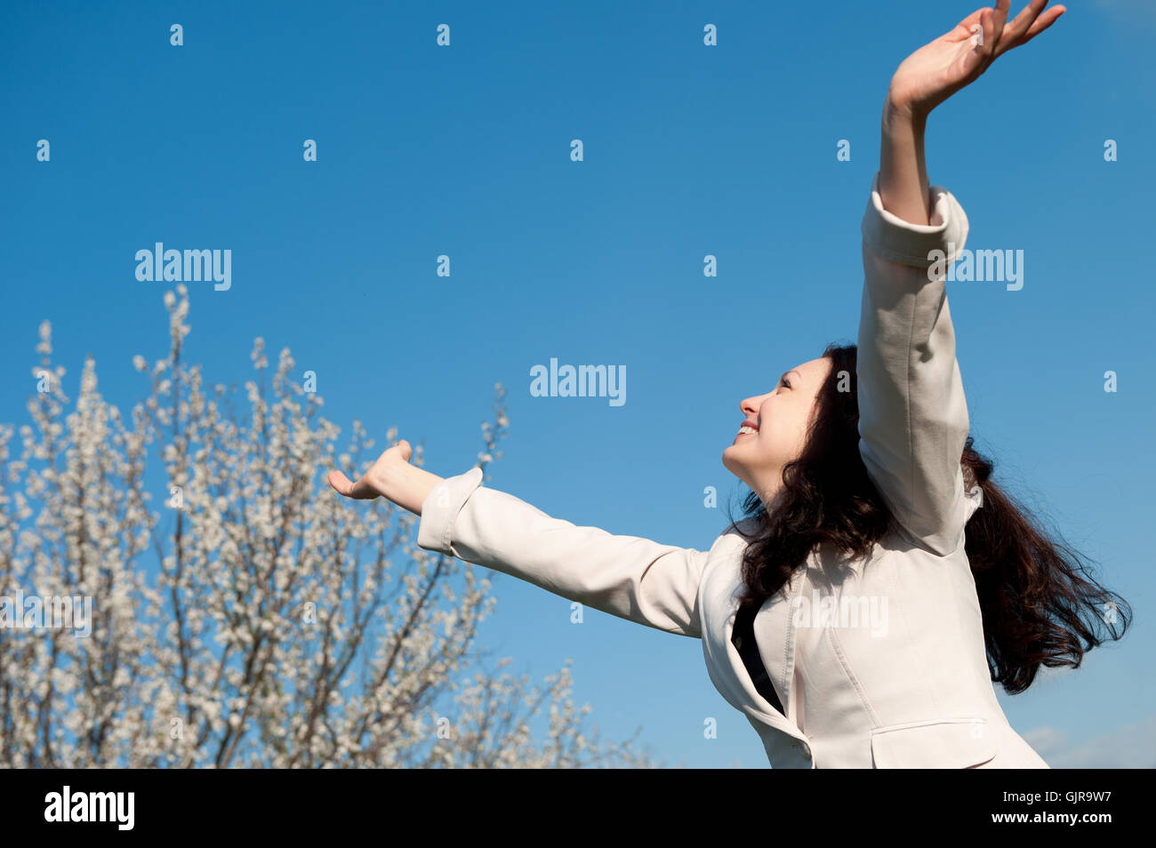 La felice donna attraente con le mani sollevate Foto Stock