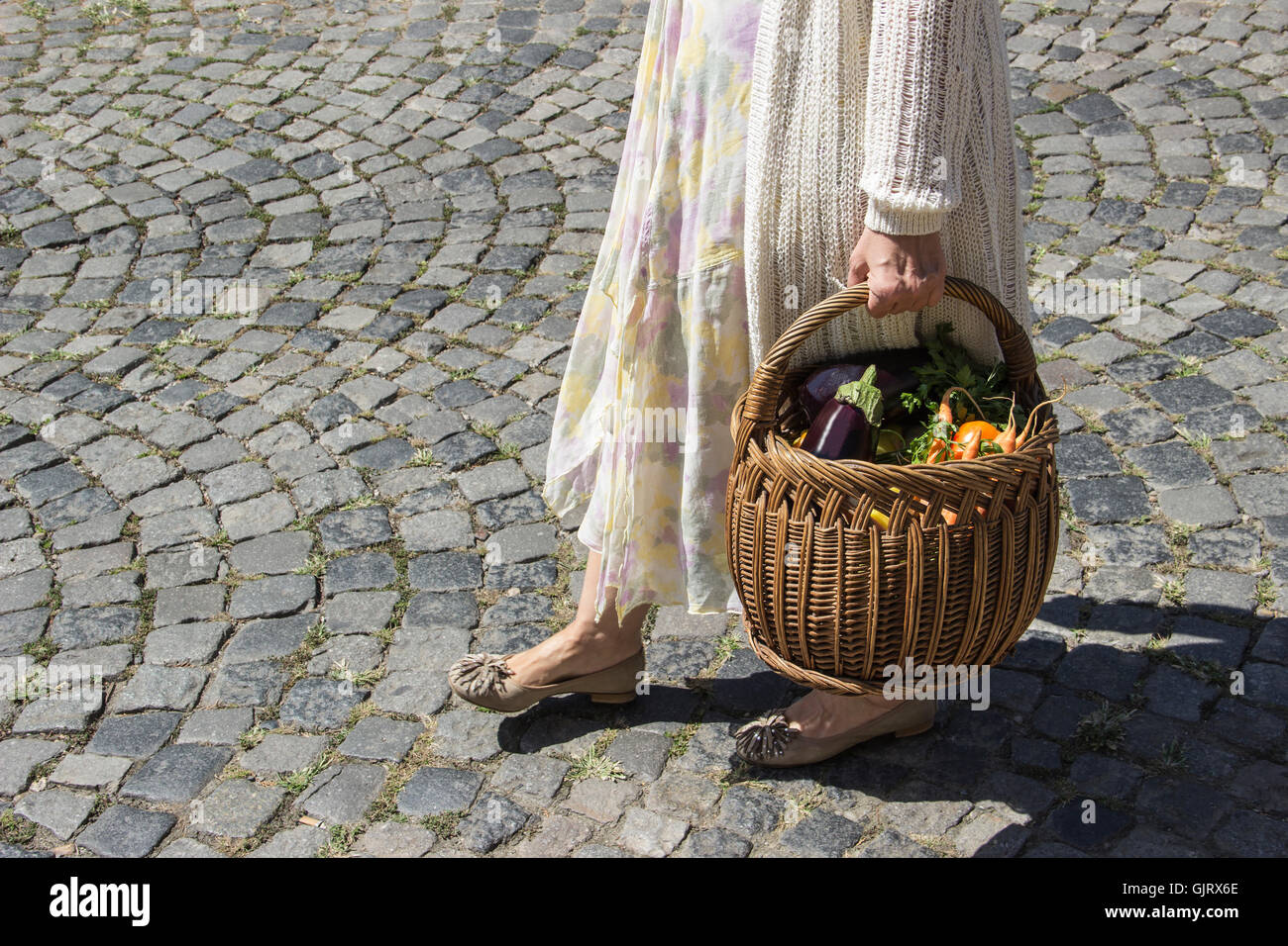 Belgrado, Serbia - Lady cammina dal mercato verde tenendo un cesto pieno di negozi di generi alimentari nella mattinata estiva Foto Stock