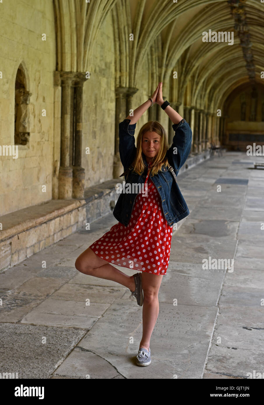 Una ragazza assume una postura yoga nei chiostri a Norwich Cathedral. Foto Stock