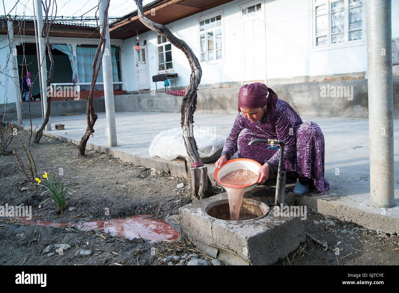 Jalabat, Kirghizistan: Donna pulisce le verdure a un al di fuori del collegamento dell'acqua. Foto Stock