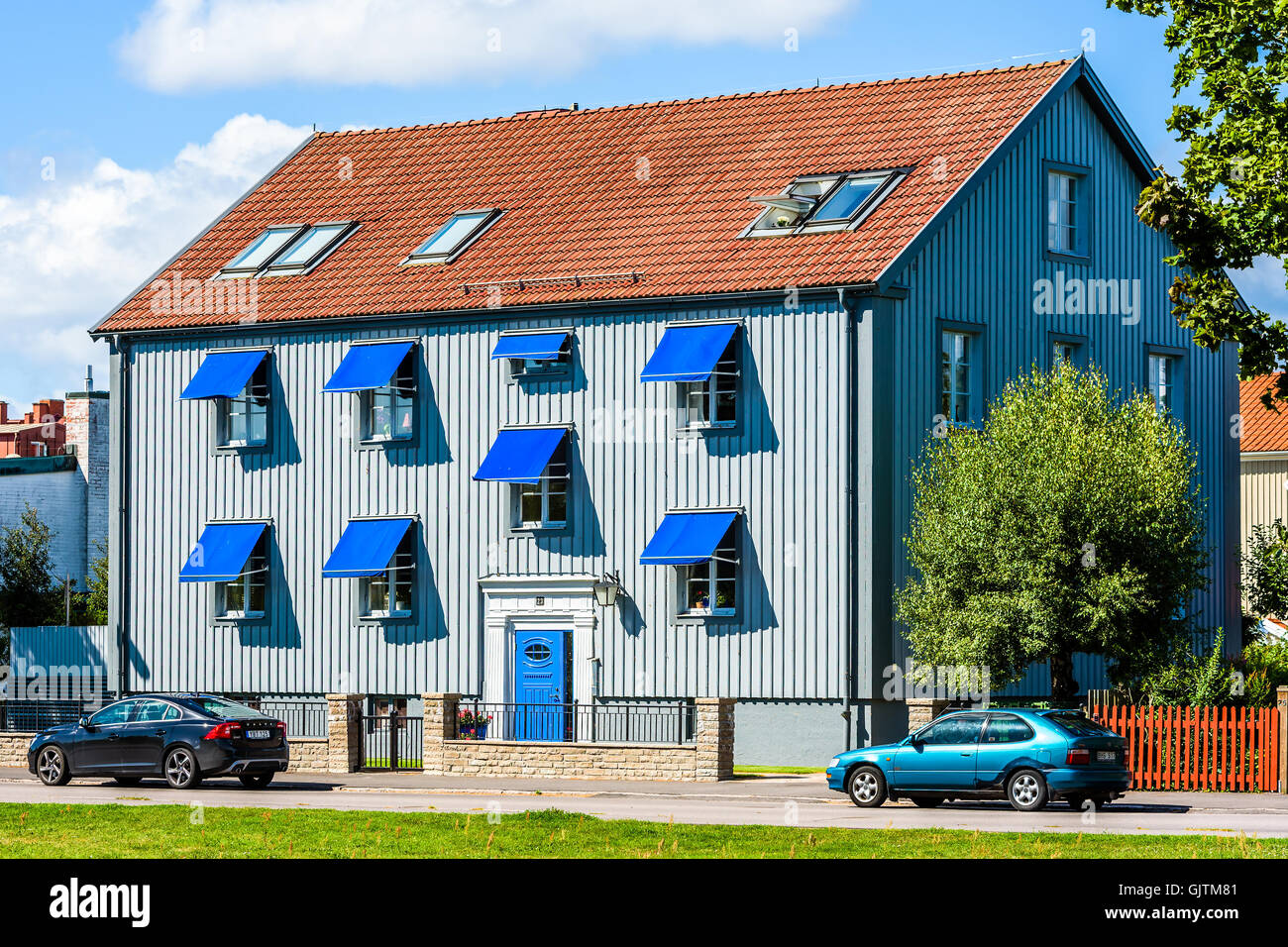 Kalmar, Svezia - Agosto 10, 2016: grigio casa con porta blu e tende. Due auto parcheggiata di fronte alla casa. Foto Stock