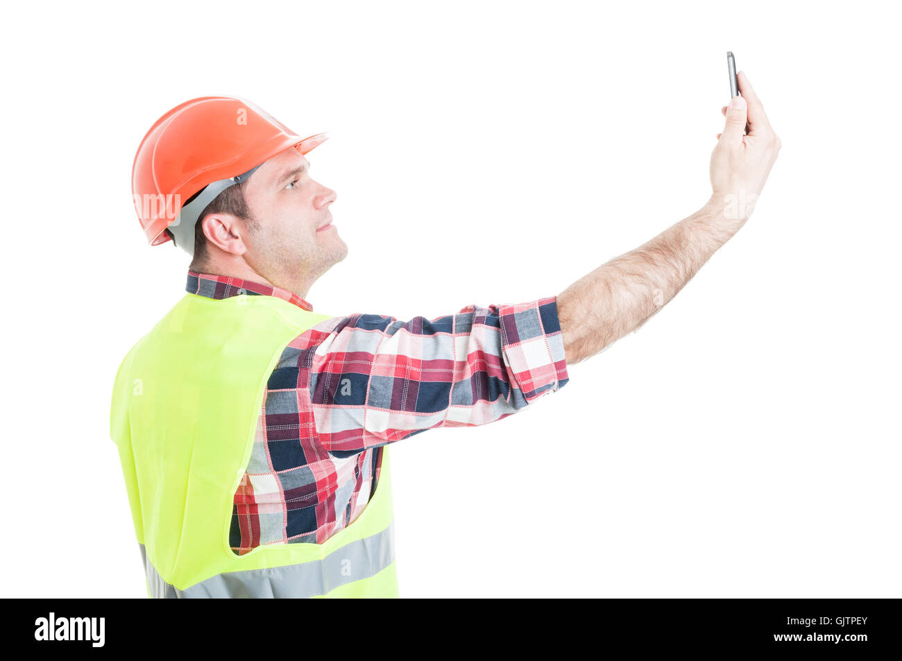 Costruttore attraente prendendo un selfie con lo smartphone e sorridente isolato su bianco di sfondo per studio Foto Stock