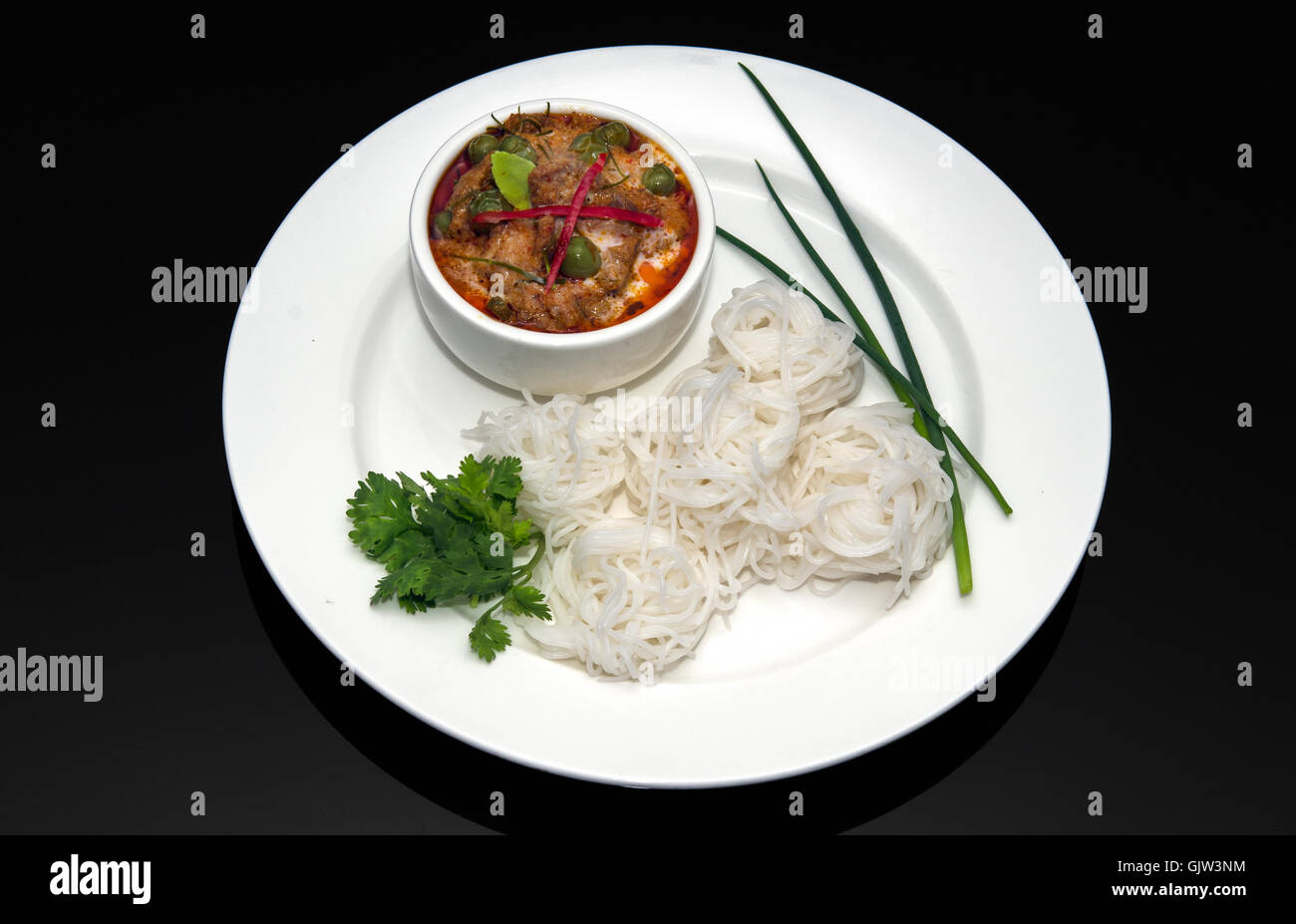 Rosso tailandese curry di manzo, bianco riso tagliatelle su sfondo nero Foto Stock