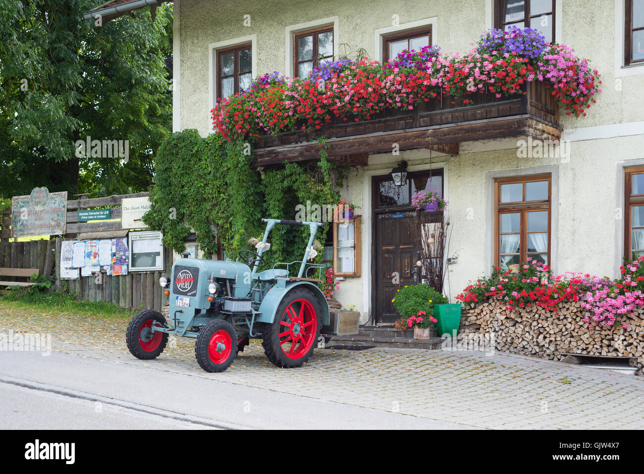 Eicher vintage Diesel trattore parcheggiato di fronte alla Lindl inn coperto con la fioritura dei gerani, Baviera, Germania Foto Stock