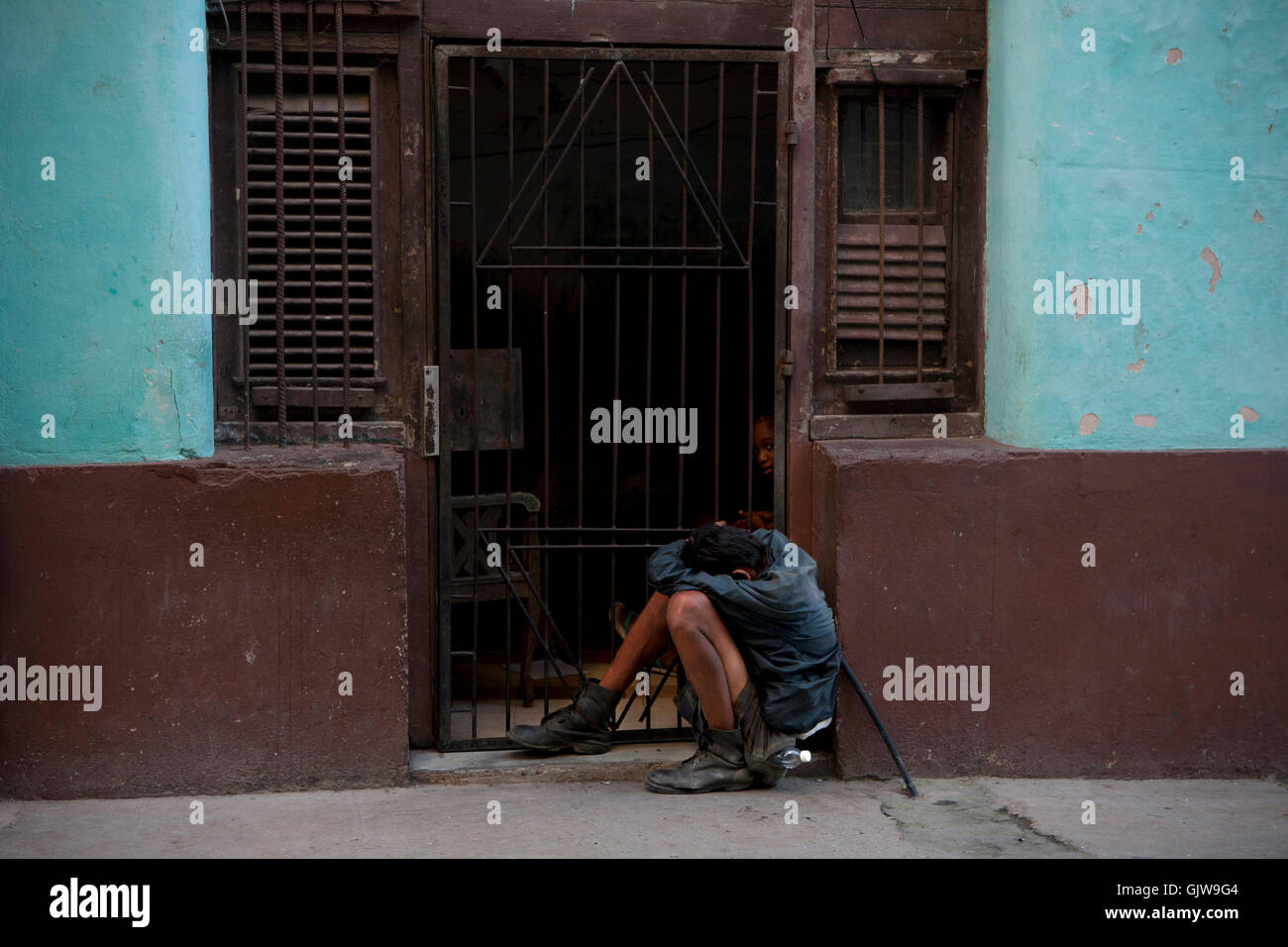 Un povero uomo dorme in una posizione da seduto su una strada nella Vecchia Havana, Cuba Foto Stock