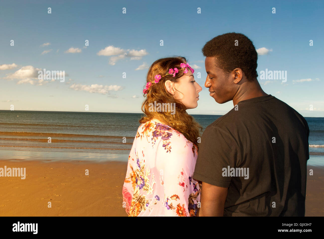 Coppia attraente multiculturale di razza mista di testa e spalle cercando in ogni altri occhi in amore sulla spiaggia emozioni romantiche Foto Stock