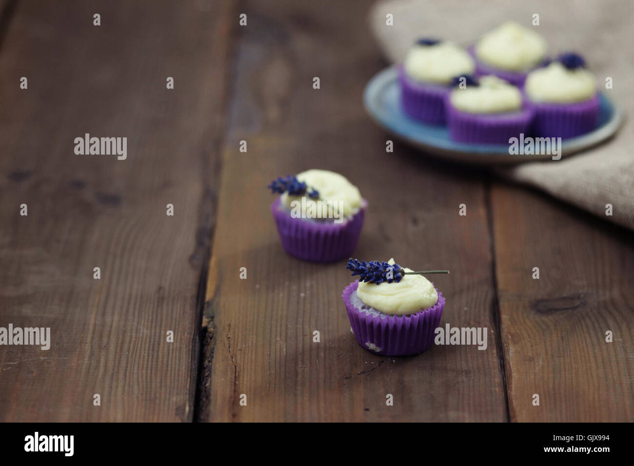 Lavanda mini tortine con mascarpone ciliegina sulla tavola di legno. Immagine ravvicinata con profondità di campo e un ampio spazio di copia. Foto Stock