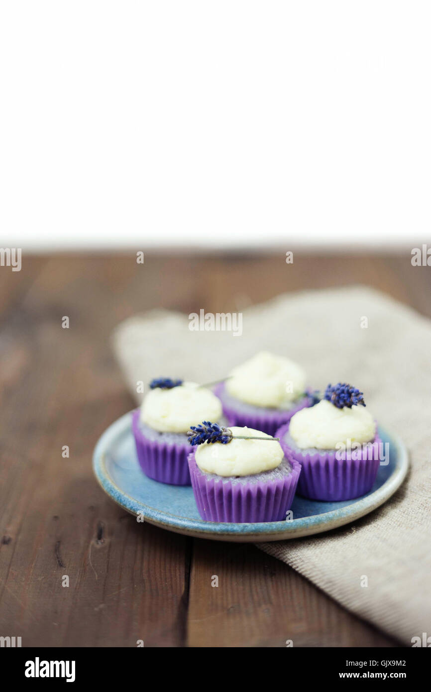 Lavanda mini tortine con mascarpone ciliegina sulla tavola di legno. Immagine ravvicinata con profondità di campo e un ampio spazio di copia. Foto Stock