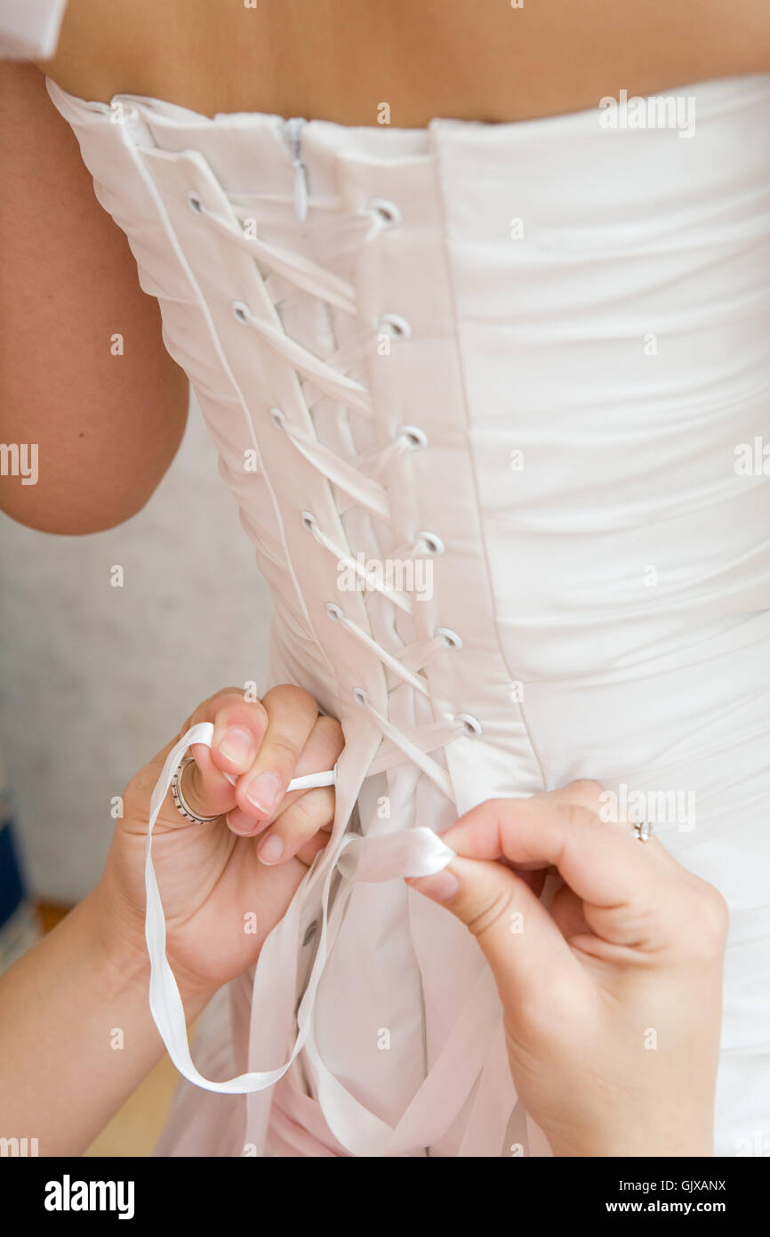 Allacciamento di un abito da sposa Foto Stock
