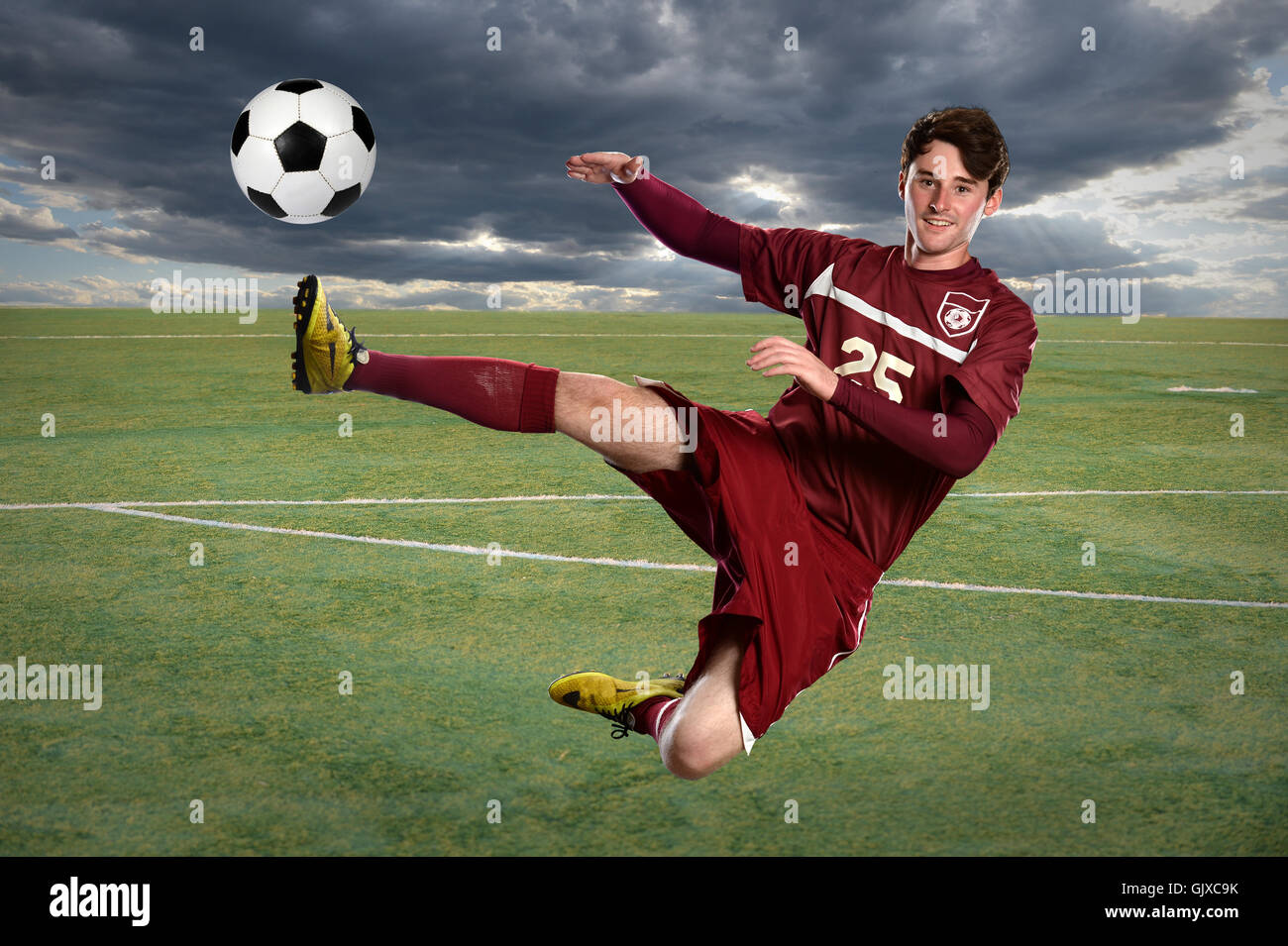 Giovane giocatore di calcio calci palla durante il salto Foto Stock Giovane giocatore di calcio calci palla durante il salto Foto Stock