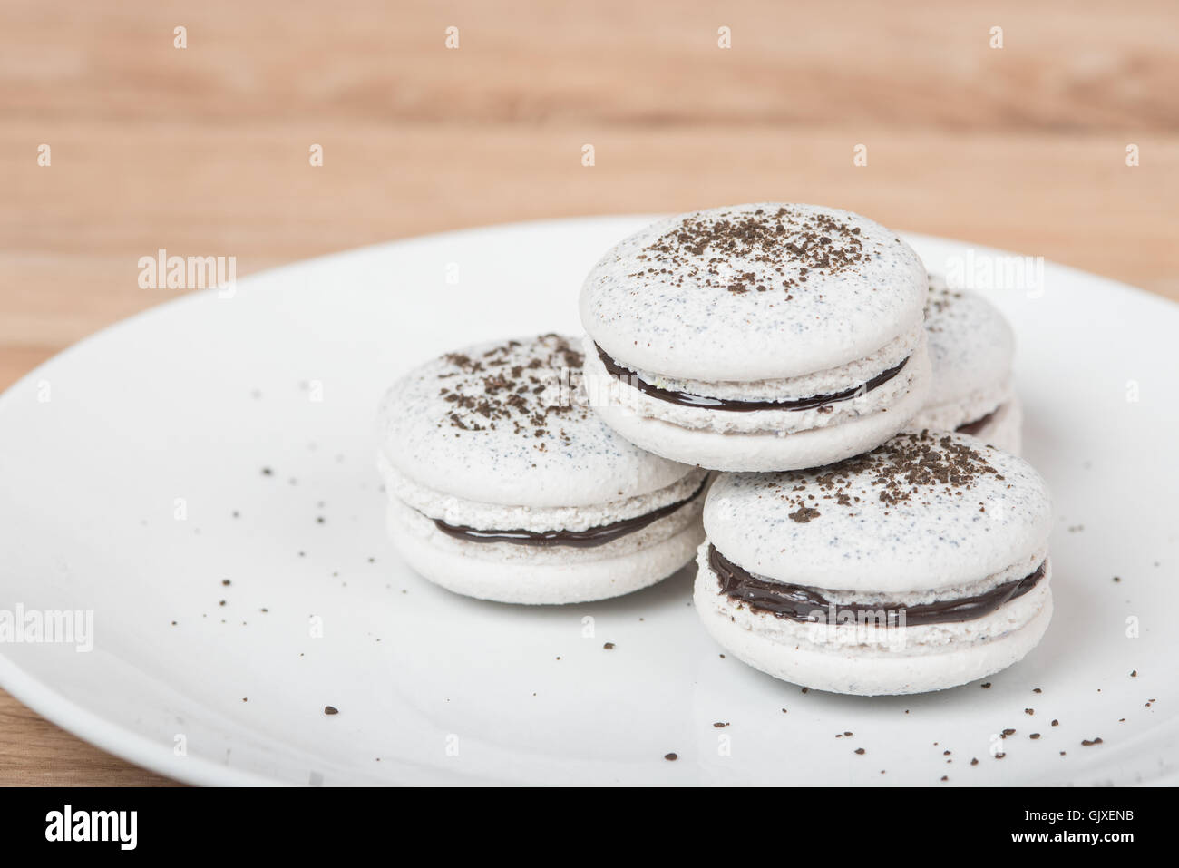 Macarons su una piastra bianca con cioccolato sbriciolati e riempimento Foto Stock