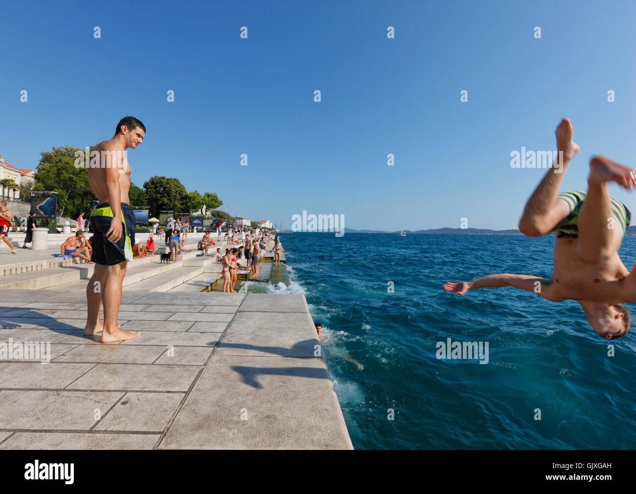 Giovane Uomo salto in acqua vicino al mare organ monumento in Zadar Foto Stock