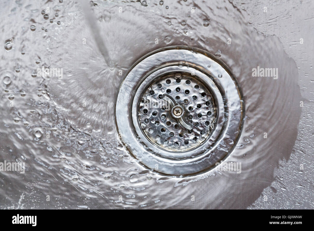 L'acqua che scorre verso il basso scarico in acciaio inox lavello da cucina lo spreco di risorse naturali Foto Stock