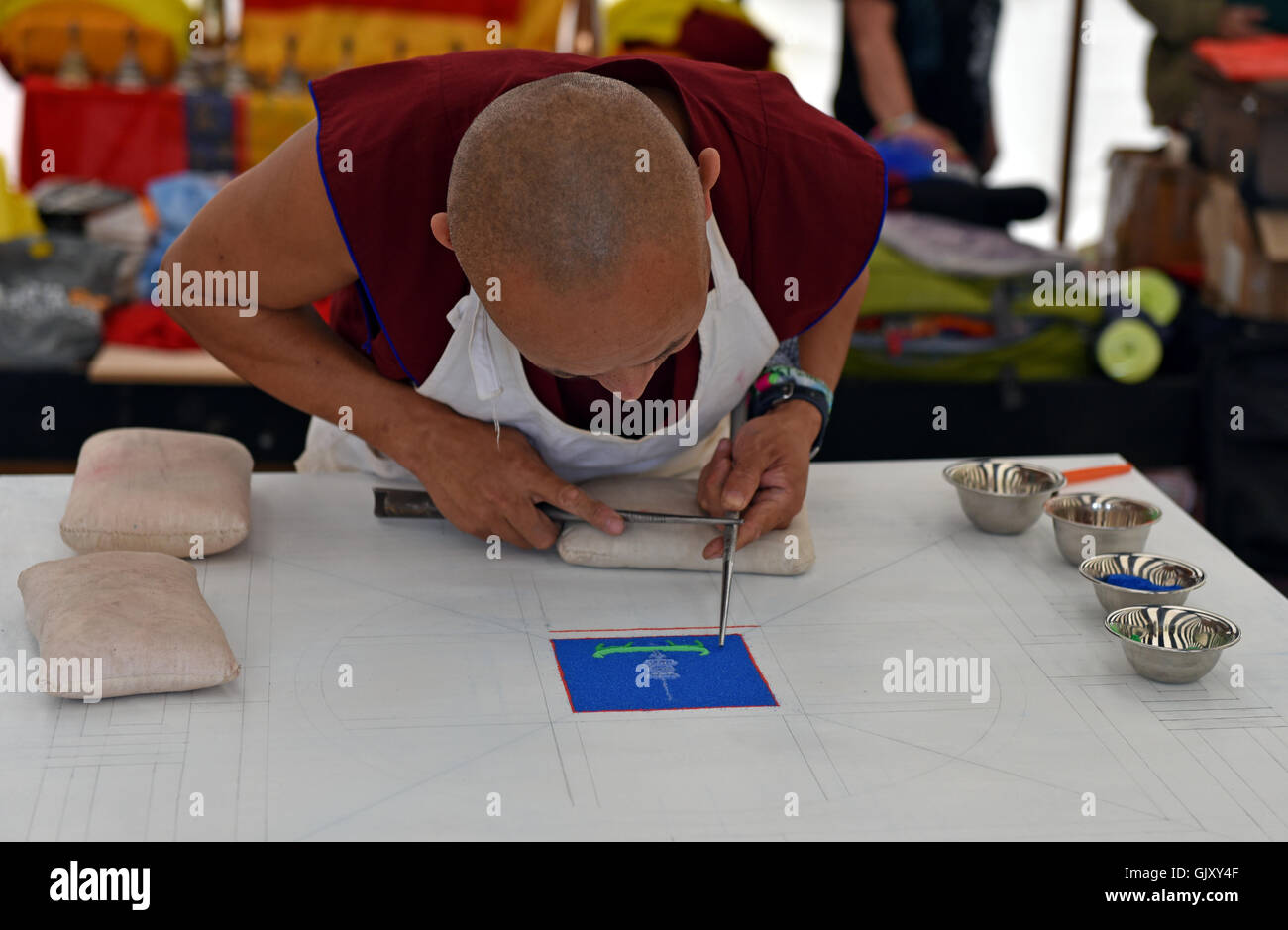 Un monaco tibetano funziona su un mandala di sabbia come parte della sua meditazione Foto Stock