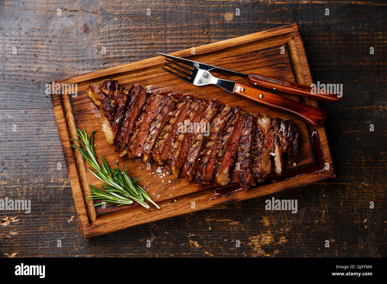 Fette di manzo alla griglia barbecue bistecca di controfiletto su tagliere in legno scuro dello sfondo Foto Stock