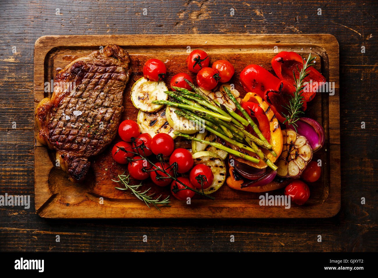 Grigliata di Black Angus Bistecca di controfiletto e verdure sul bordo di taglio su sfondo di legno Foto Stock