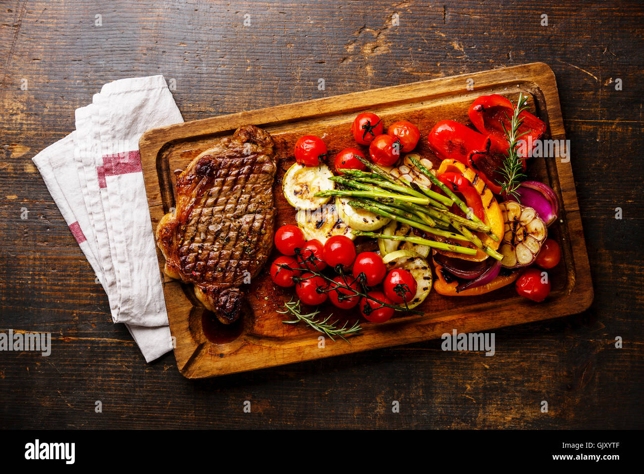 Grigliata di Black Angus Bistecca di controfiletto e verdure sul bordo di taglio su sfondo di legno Foto Stock