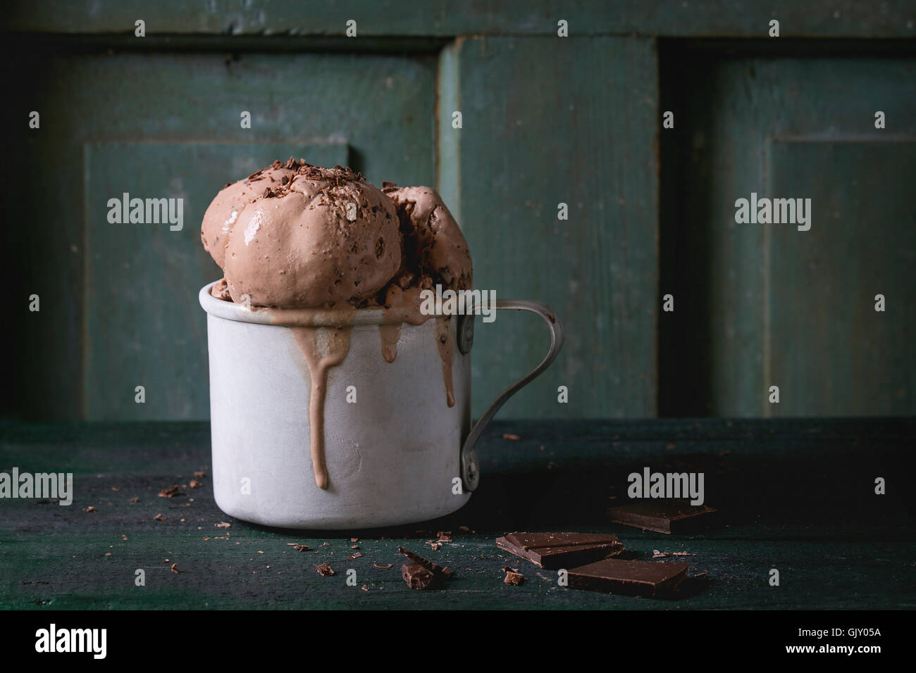 Congelati vintage tazza di alluminio con cioccolato fondente gelati sfere, servita con cioccolato fondente tritato sul vecchio tavolo in legno. Dark Foto Stock