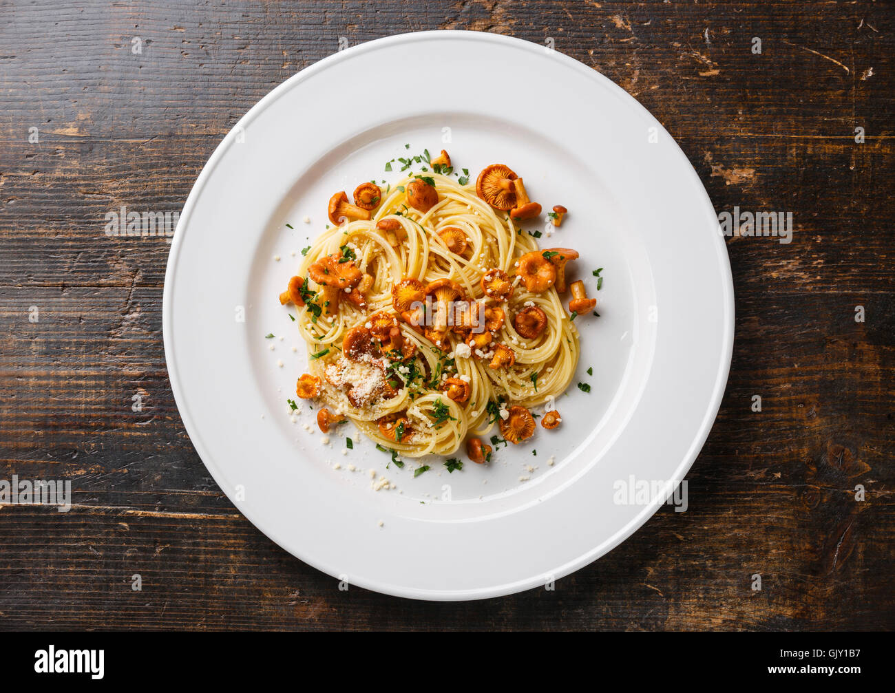 Pasta spaghetti con bosco selvatico funghi Chanterelle sulla piastra bianca sul tavolo di legno Foto Stock