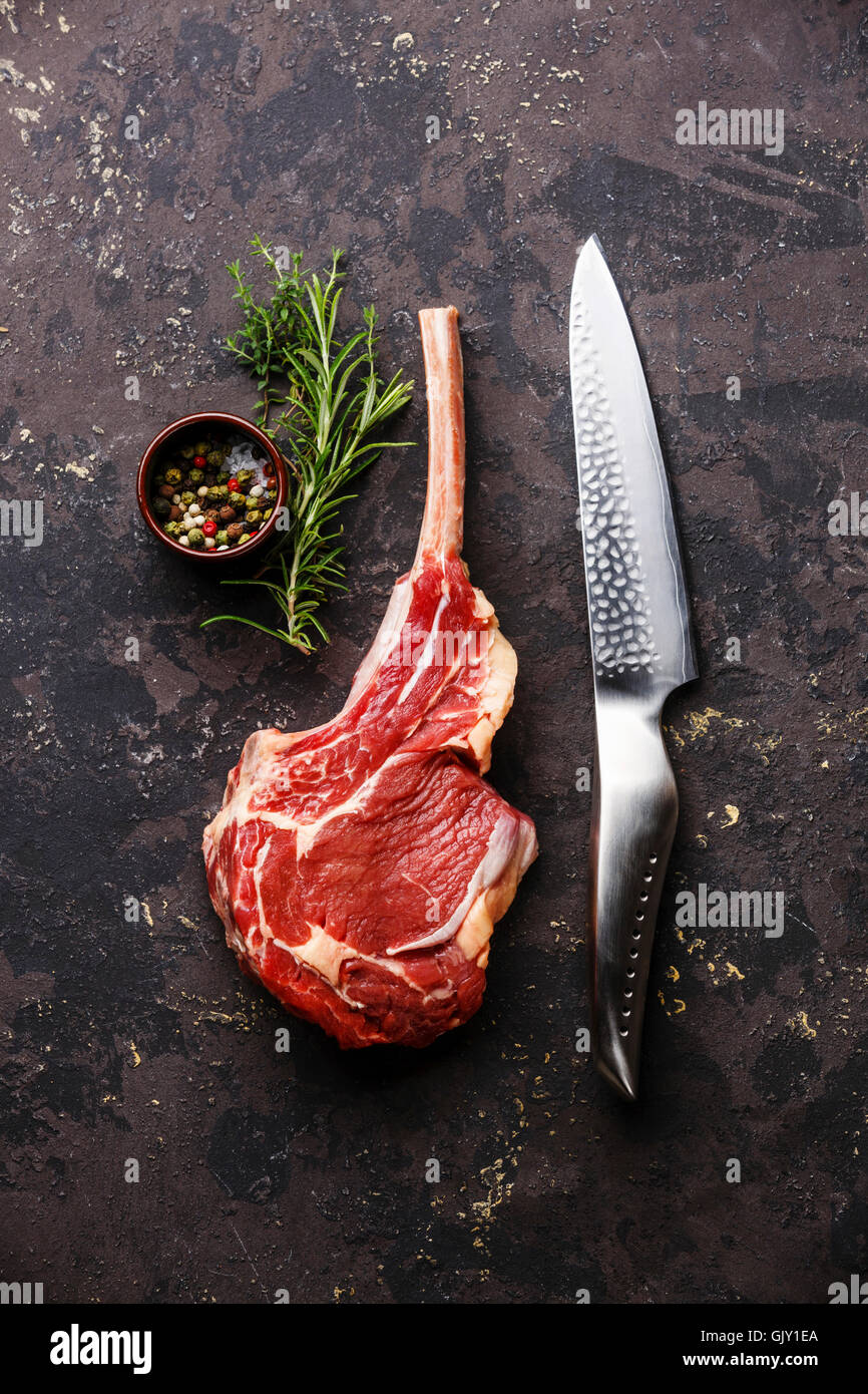 Materie di carni fresche bovine nervatura bistecca su osso e coltello da cucina su sfondo scuro Foto Stock