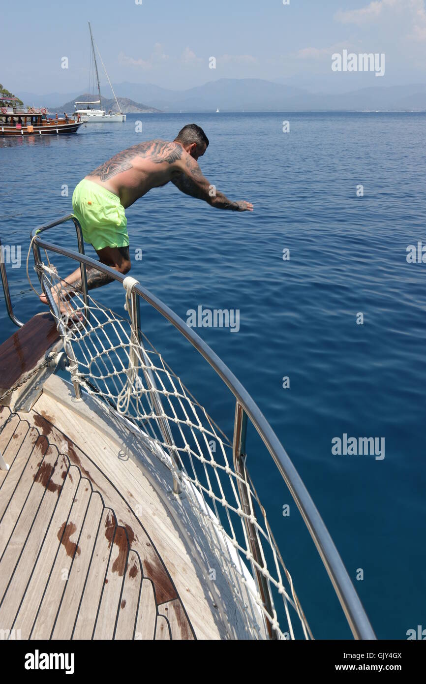 Un uomo le immersioni in mare dal lato di una barca Foto Stock
