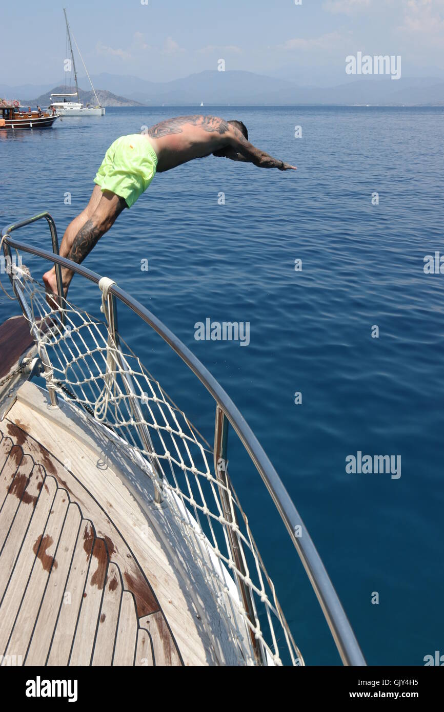 Un uomo le immersioni in mare dal lato di una barca Foto Stock