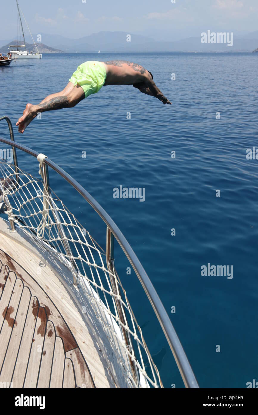 Un uomo le immersioni in mare dal lato di una barca Foto Stock