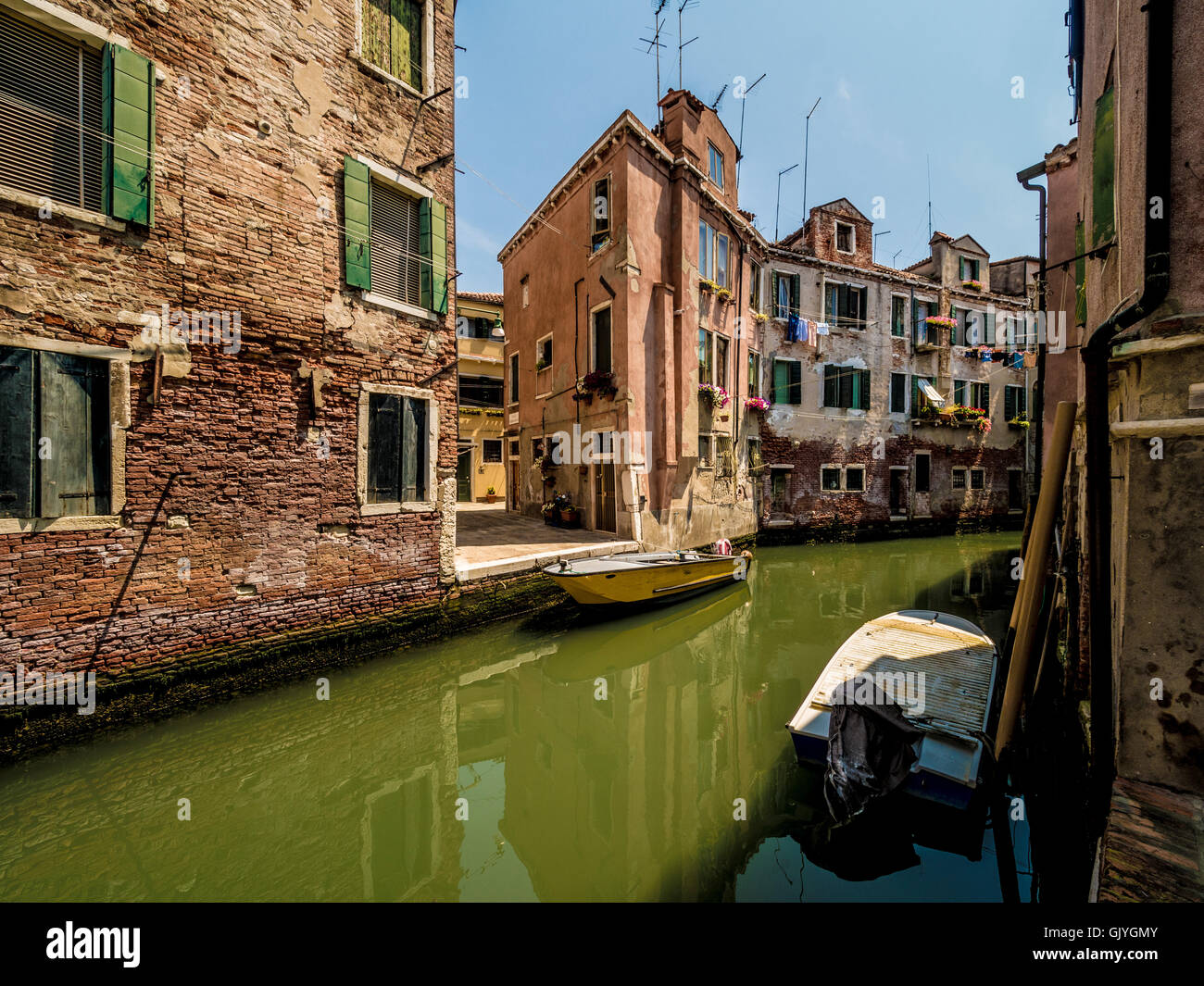 Barche ormeggiate su uno stretto canale con edifici tradizionali su entrambi i lati. Venezia, Italia. Foto Stock
