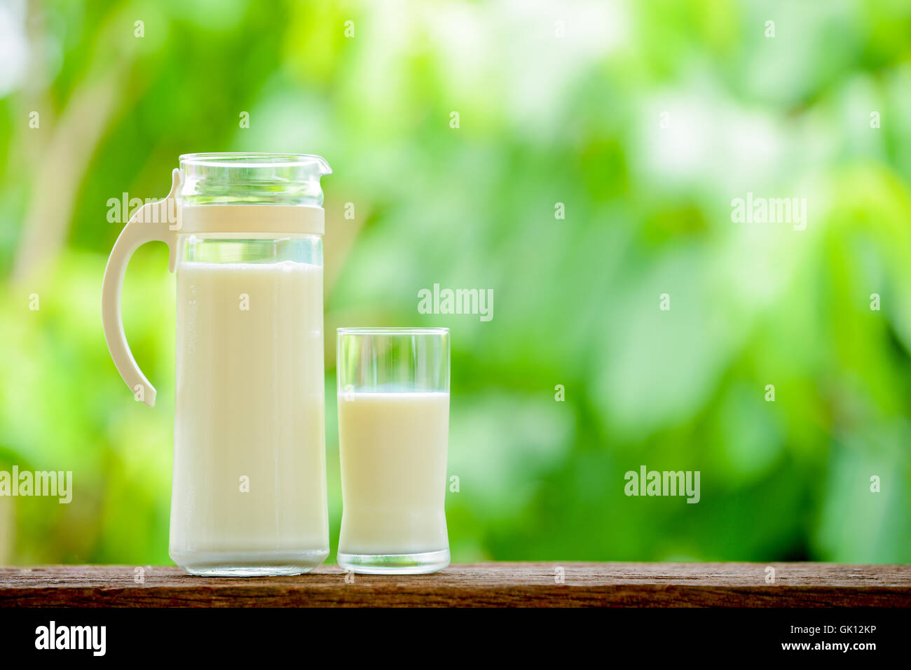 Bricco per latte con vetro su tavola con lo sfondo della natura Foto Stock