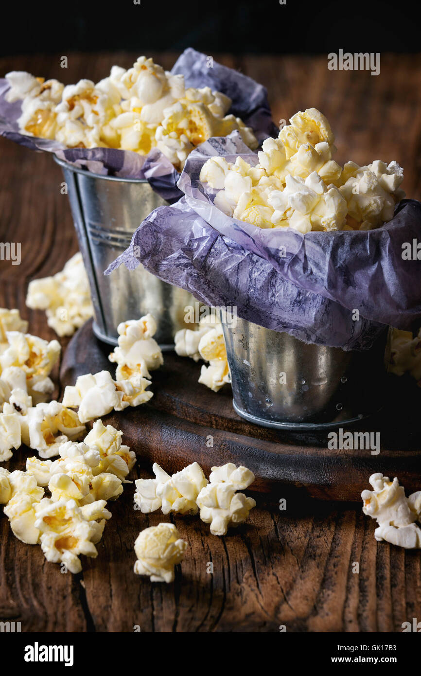 Preparate popcorn salata è servita in piccole benne con all'interno di carta su legno tagliere su legno scuro dello sfondo. Foto Stock