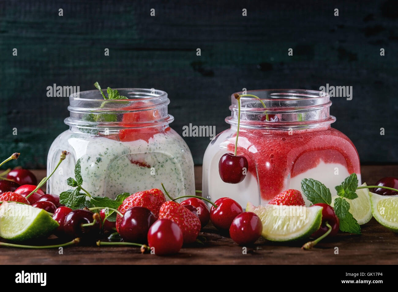 Piazza due vasi di vetro con yogurt fatto in casa con la menta, purea di fragole, ciliegio e semi di chia servita con frutti di bosco freschi e SLI Foto Stock