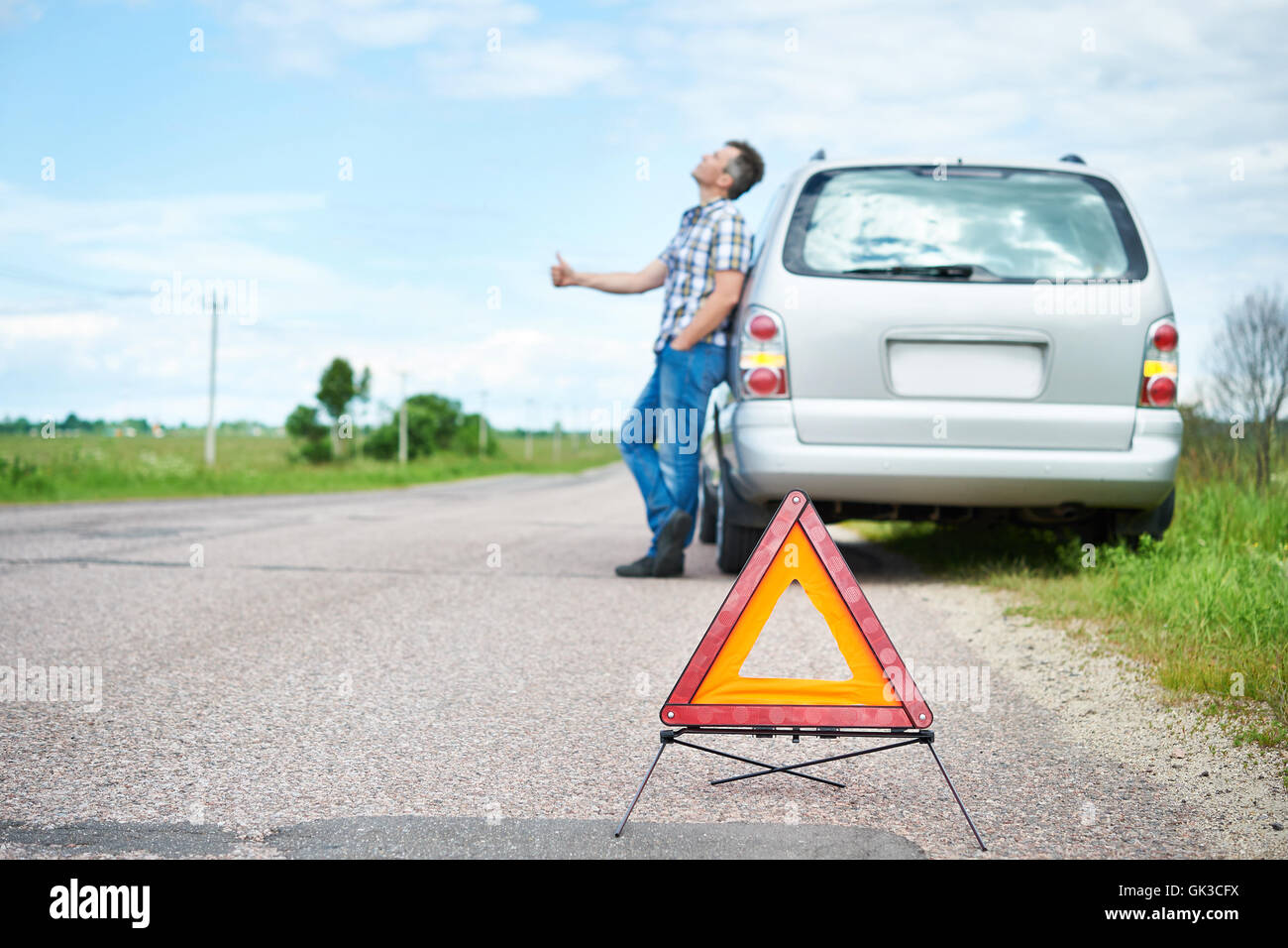 Segno di emergenza e uomo in piedi sulla strada nei pressi di auto in attesa help Foto Stock