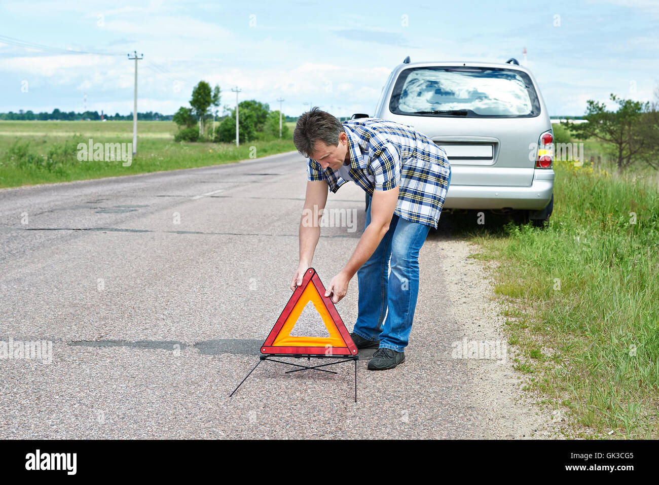 L'uomo installazione di segno di emergenza sulla strada vicino alla sua vettura in attesa help Foto Stock