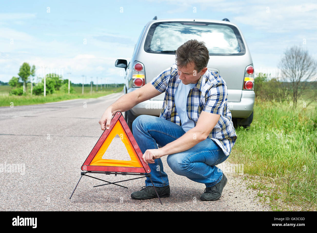 L'uomo installazione di segno di emergenza sulla strada vicino alla sua vettura in attesa help Foto Stock