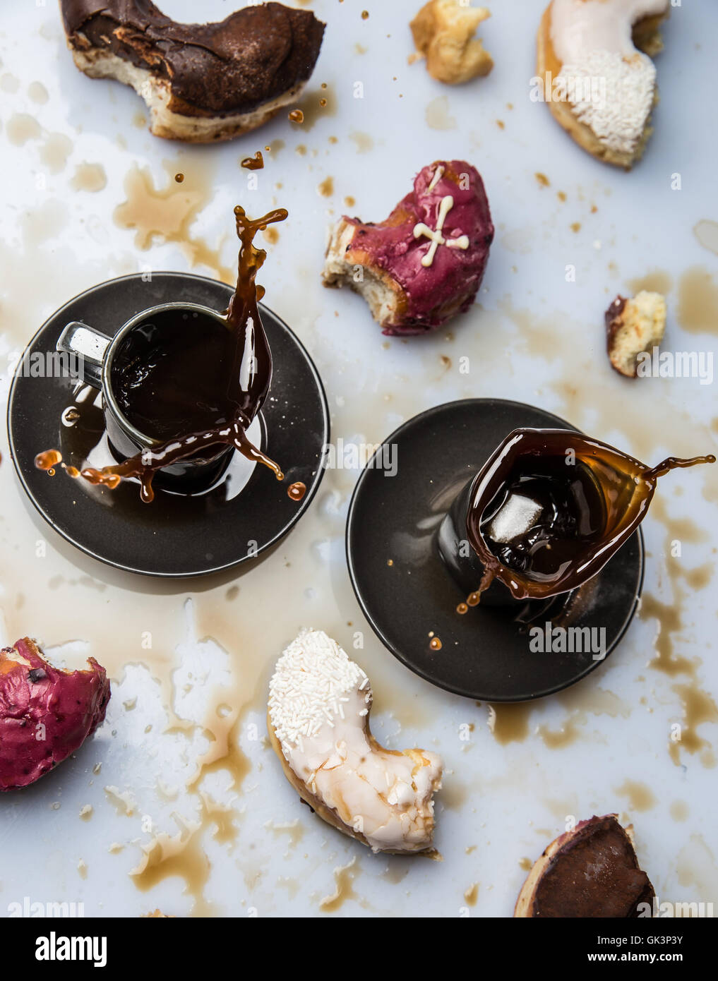 Pezzi di ciambelle e due tazze di caffè in uno sfondo bianco Foto Stock