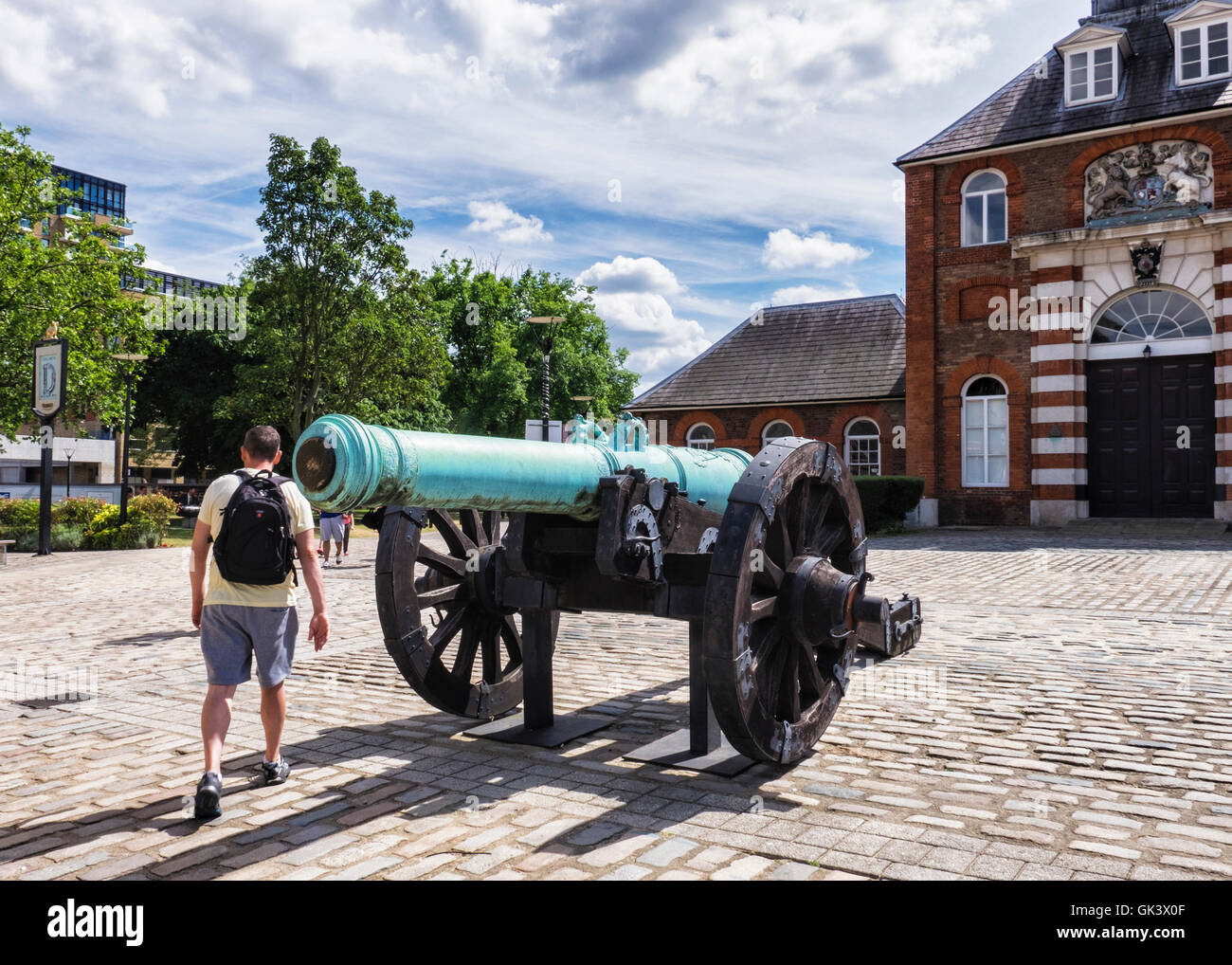 Woolwich, Londra. Giovane uomo cammina passato il Royal fonderia di ottone esterno dell'edificio e canon al Regio Arsenale Riverside, Foto Stock