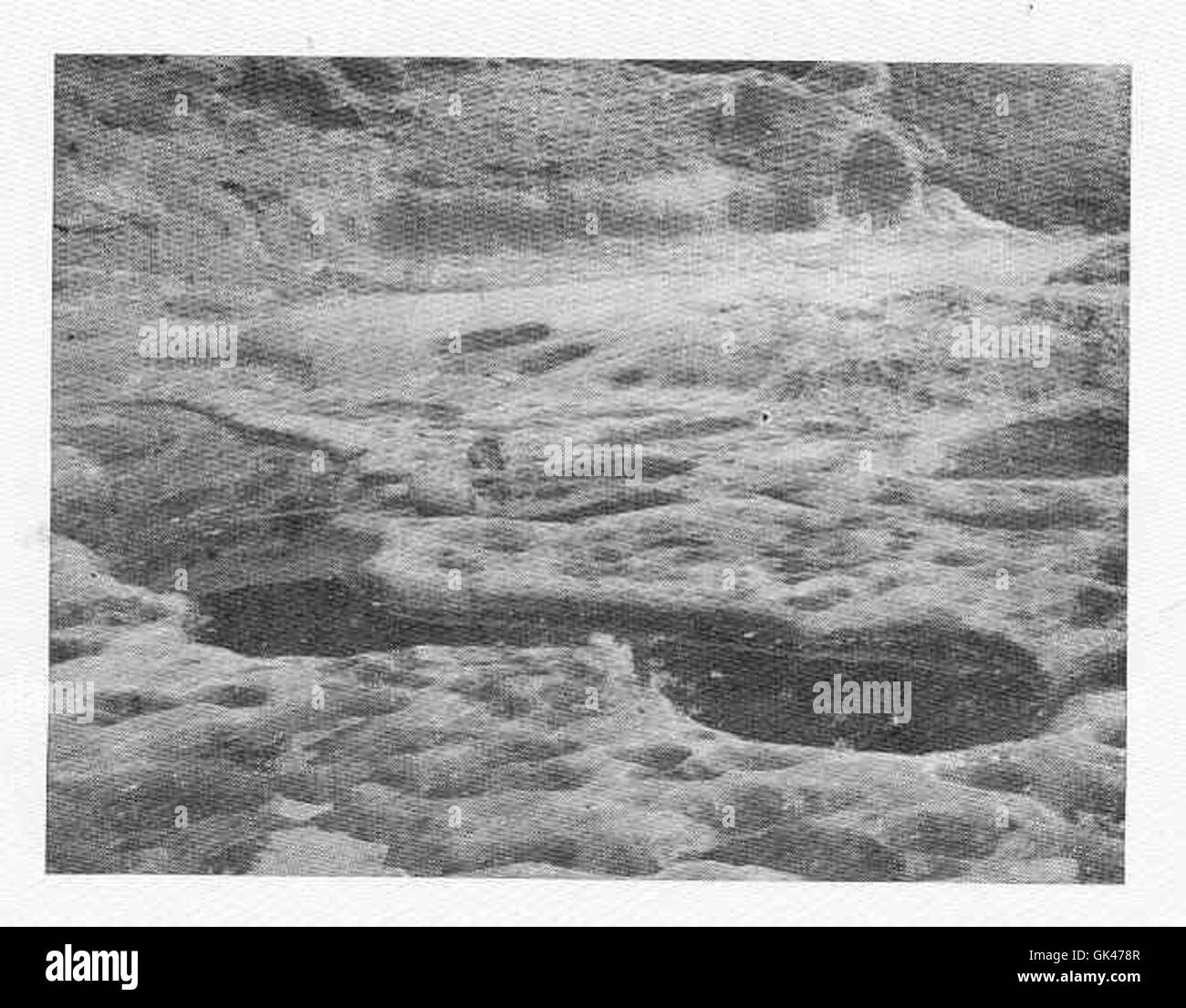 Piccole depressioni in arenaria vicino alla linea dell'acqua alta, probabilmente formate dall'erosione e dall'azione mareale. Queste caratteristiche sono comuni nella geologia costiera e forniscono informazioni sui processi ambientali. Foto Stock
