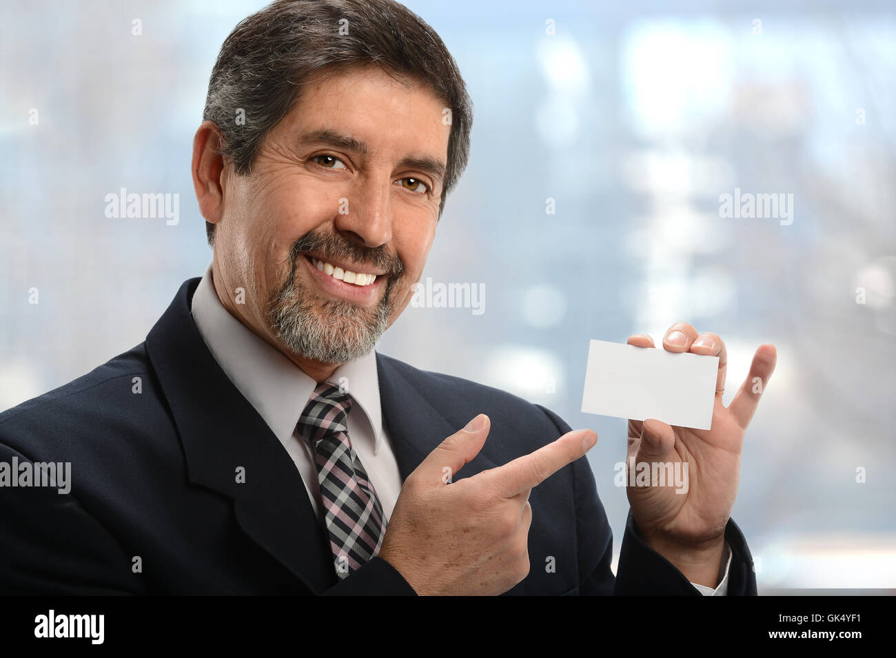 Ritratto di senior imprenditore ispanica che puntano a blank business card all'interno di office Foto Stock