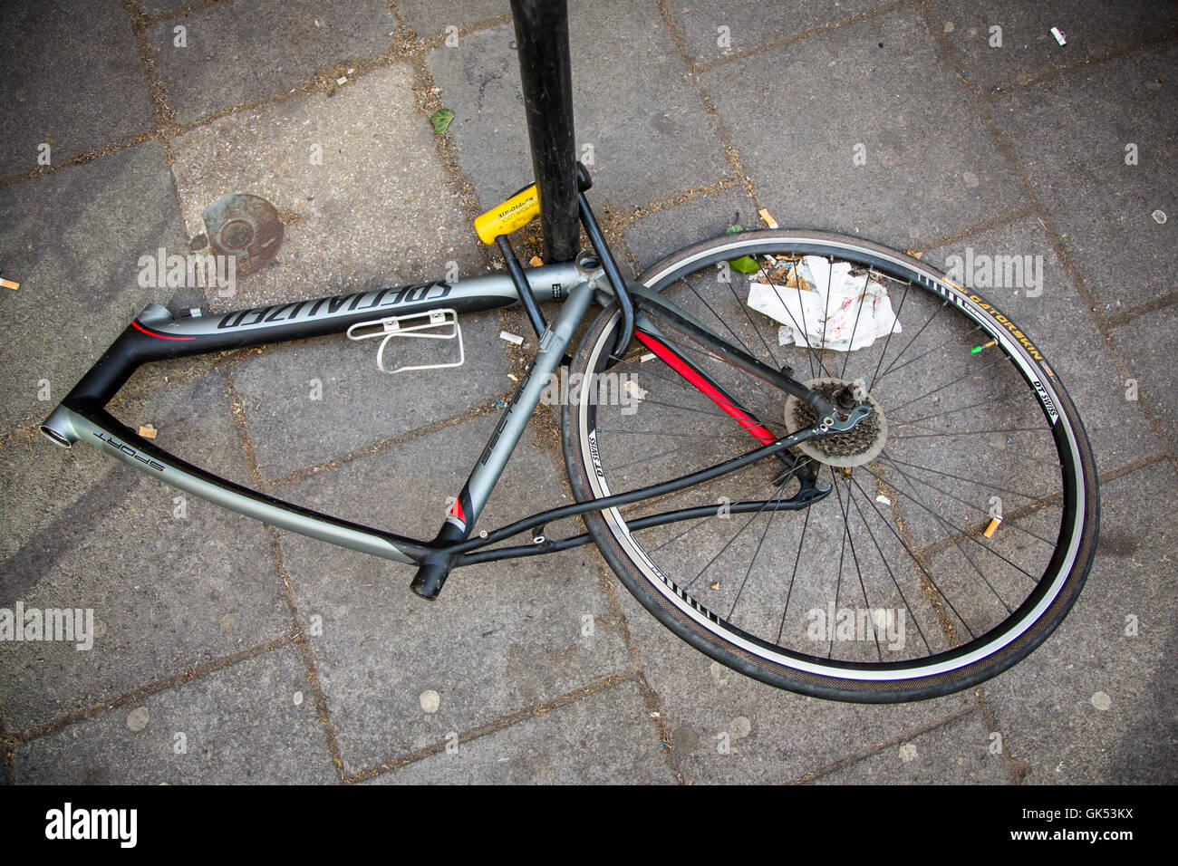 Una ruota e il telaio bloccato da una lampada posta sono tutto ciò che è a  sinistra di una bicicletta che è stato spogliato delle sue parti Foto stock  - Alamy