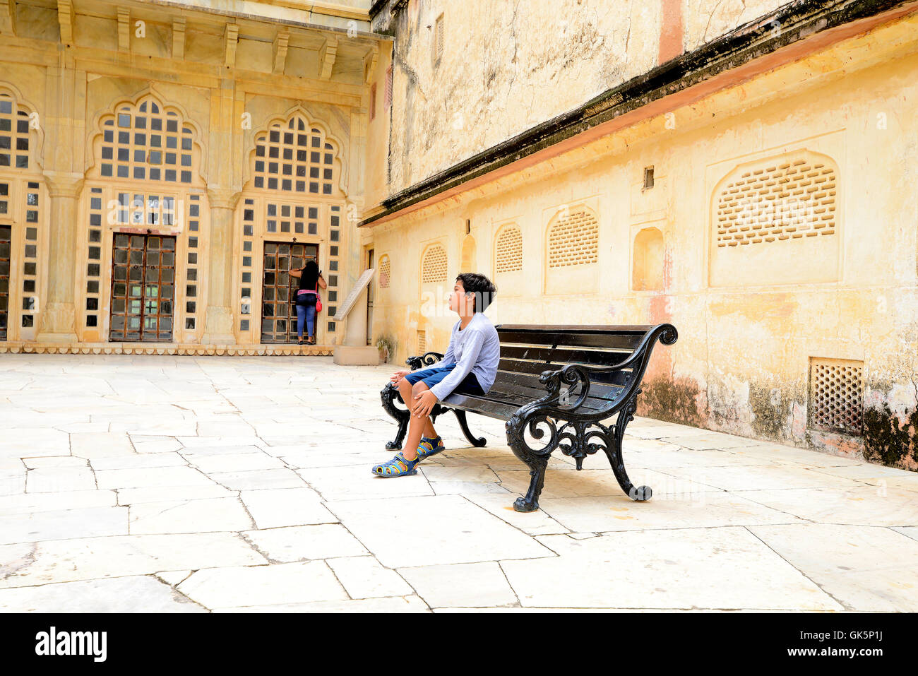 Un bambino seduto da solo su un giardino con sedie in Forte Amber, Jaipur, Rajasthan, India. Foto Stock