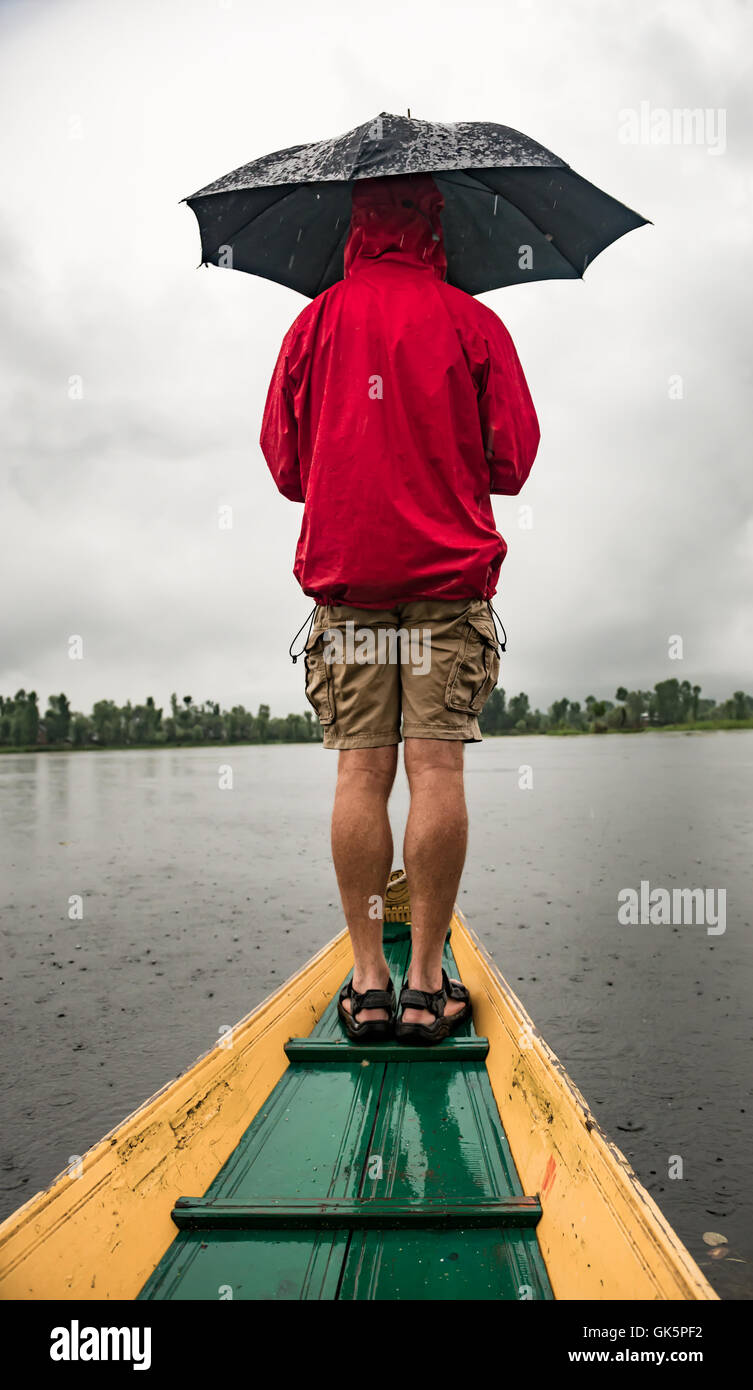 Uomo con ombrello in piedi sulla prua di una barca sul lago dal Kashmir India Foto Stock