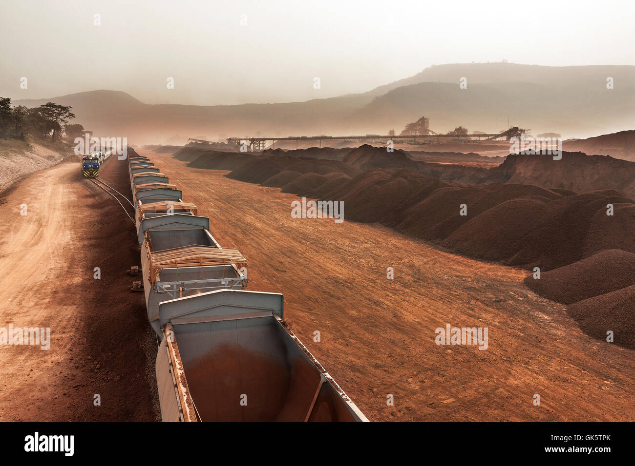 Svuotare i vagoni di minerale che arrivano a fungo della rotaia per il caricamento con il minerale di ferro. Treno caricato sull'ansa a distanza in attesa di partenza per porta per spedizione oltremare. Foto Stock