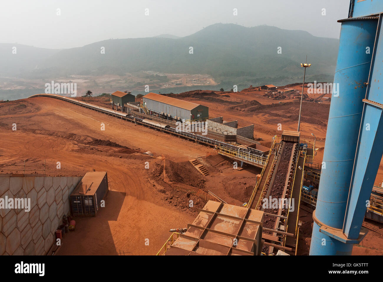 La produzione di minerali di ferro. Dal minerale di ematite frantoio impianto e la tramoggia. Vista del trasportatore principale e giù per la collina di miniera di uffici e di impianto di trasformazione area. Foto Stock