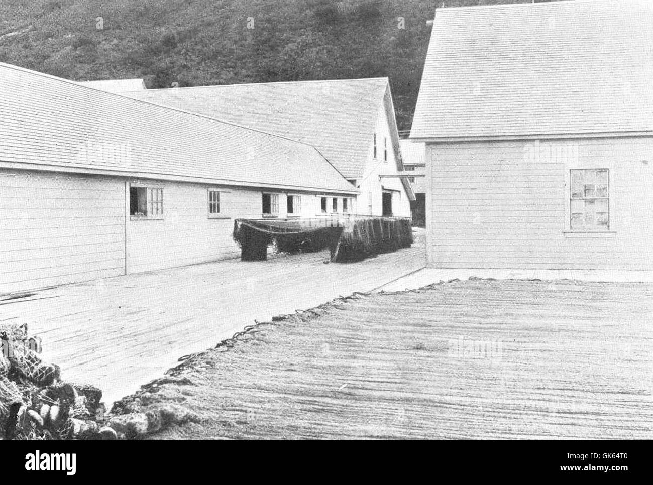 È raffigurata una conserviera sull'isola di Kodiak, che mostra le reti da pesca essiccate. L'isola di Kodiak è nota per la sua significativa industria della pesca, in particolare nel salmone, con le conserve che svolgono un ruolo chiave nella lavorazione e nella conservazione dei prodotti marini. Foto Stock