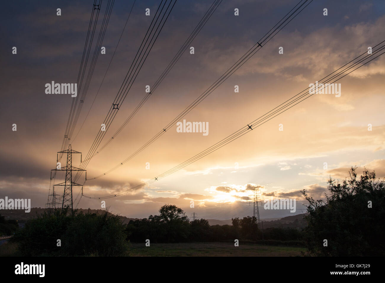 Elettricità tralicci e linee di potenza ar crepuscolo con un moody sky ambientali Foto Stock