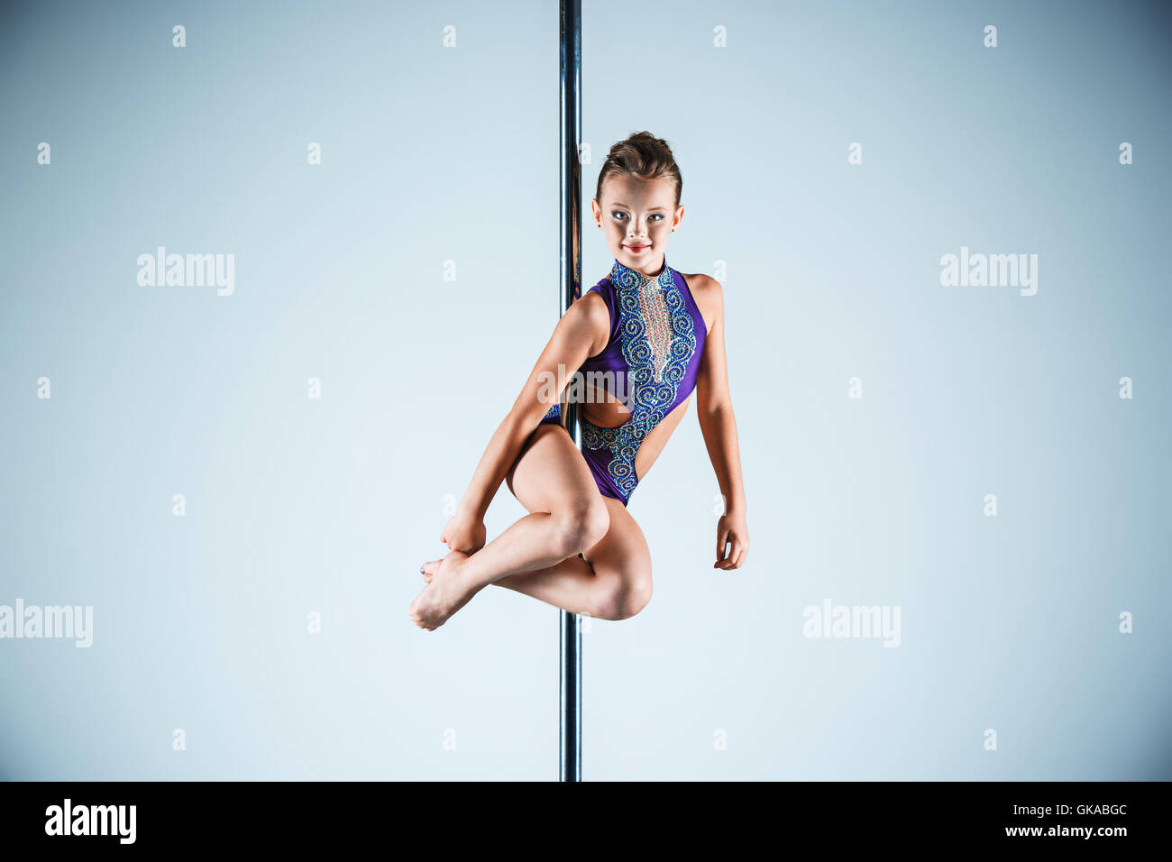 Il forte e graziosa fanciulla di eseguire esercizi acrobatici sul pilone Foto Stock