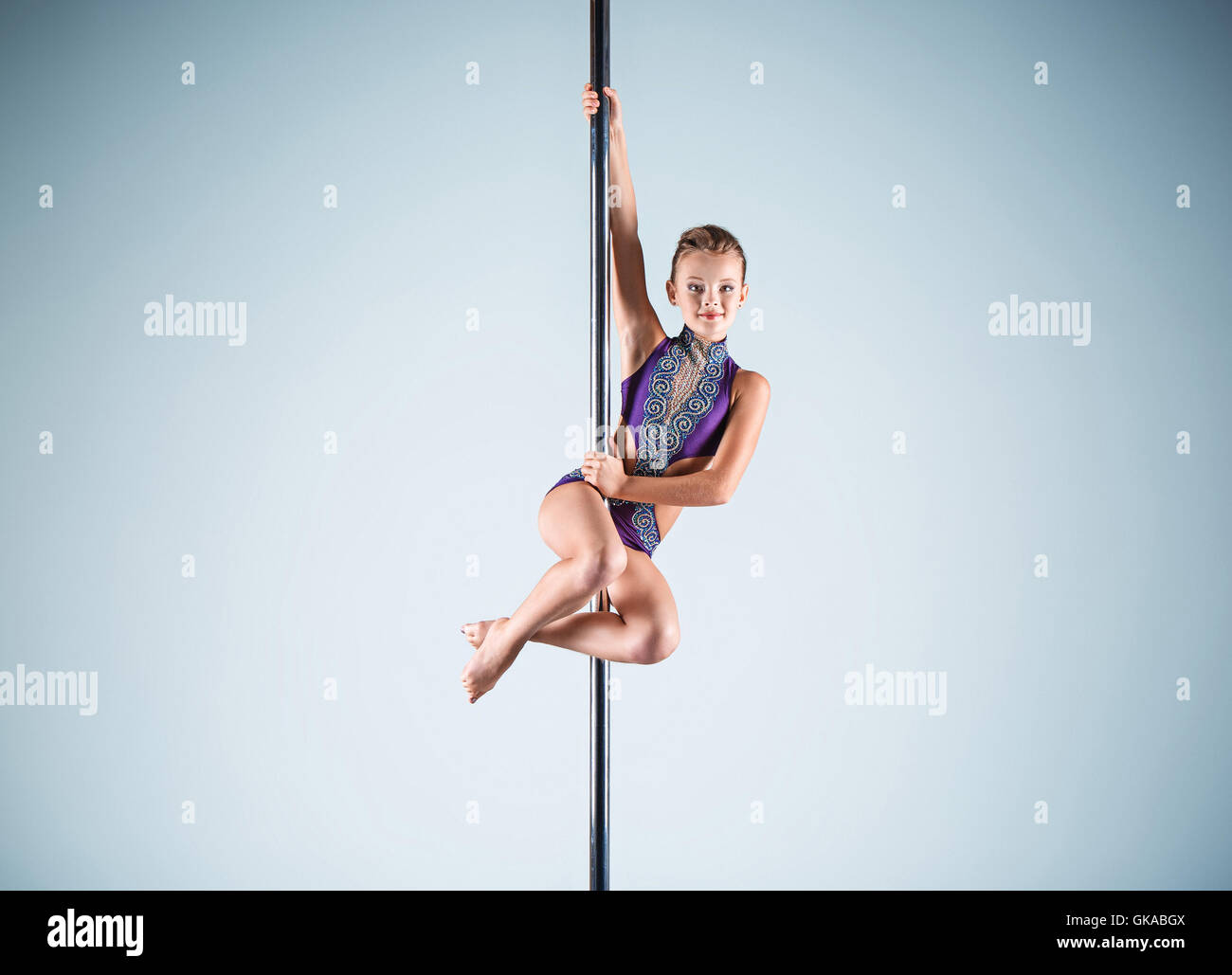 Il forte e graziosa fanciulla di eseguire esercizi acrobatici sul pilone Foto Stock